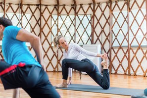 A yoga class in a room with wooden floors and a lattice partition.