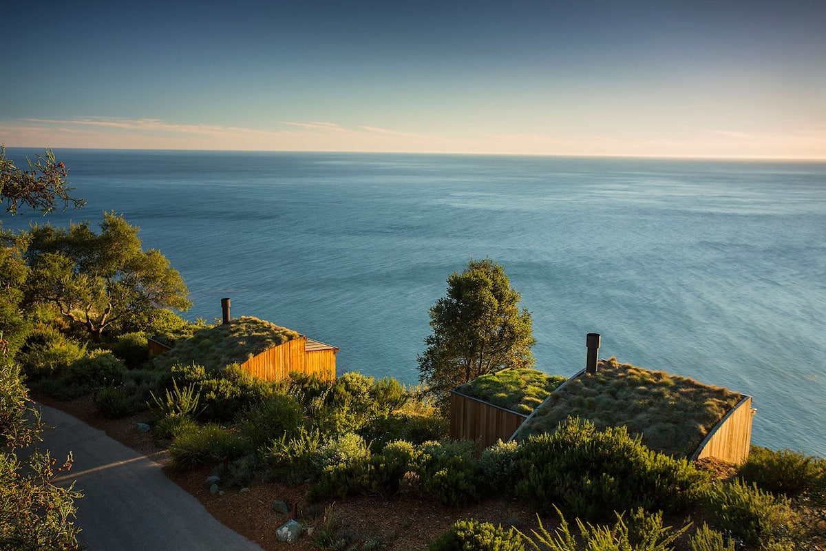 A coastal property with a paved driveway, wooden cabins, and a view of the ocean.