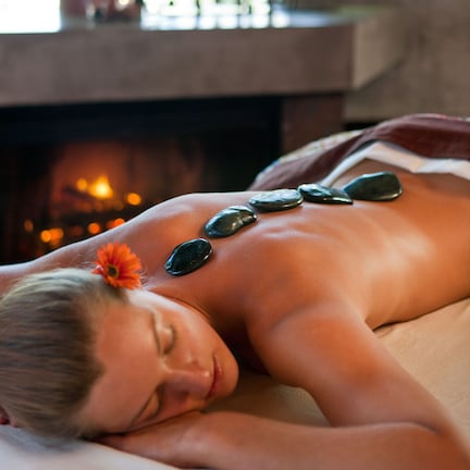 A person receiving a stone massage with a fireplace in the background.