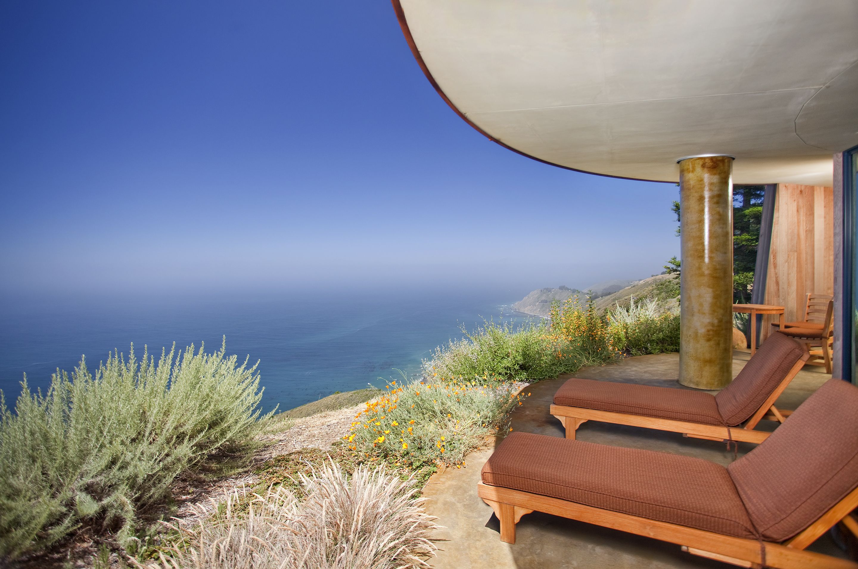 A seaside terrace with lounge chairs and a view of the ocean.