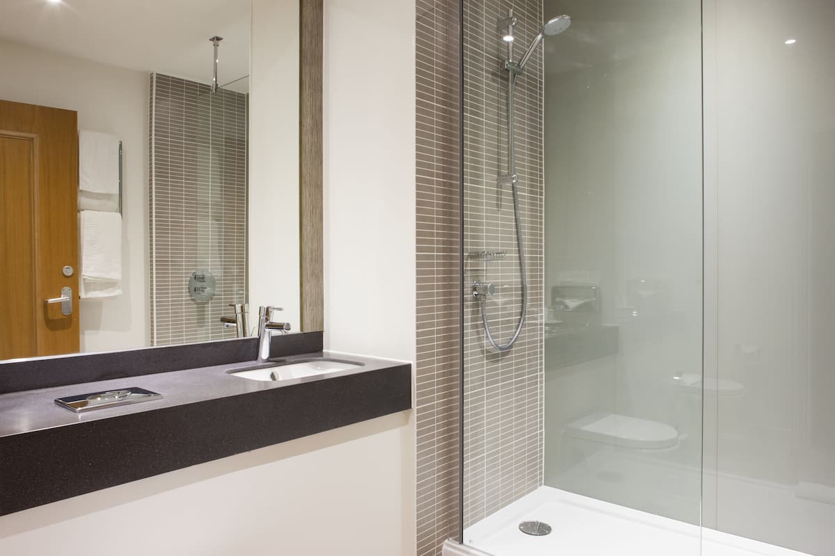 Une salle de bain moderne avec une douche à parois de verre, un lavabo et un miroir.