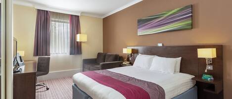 A hotel room with a large bed, a desk, a chair, a sofa, and a painting on the wall.
