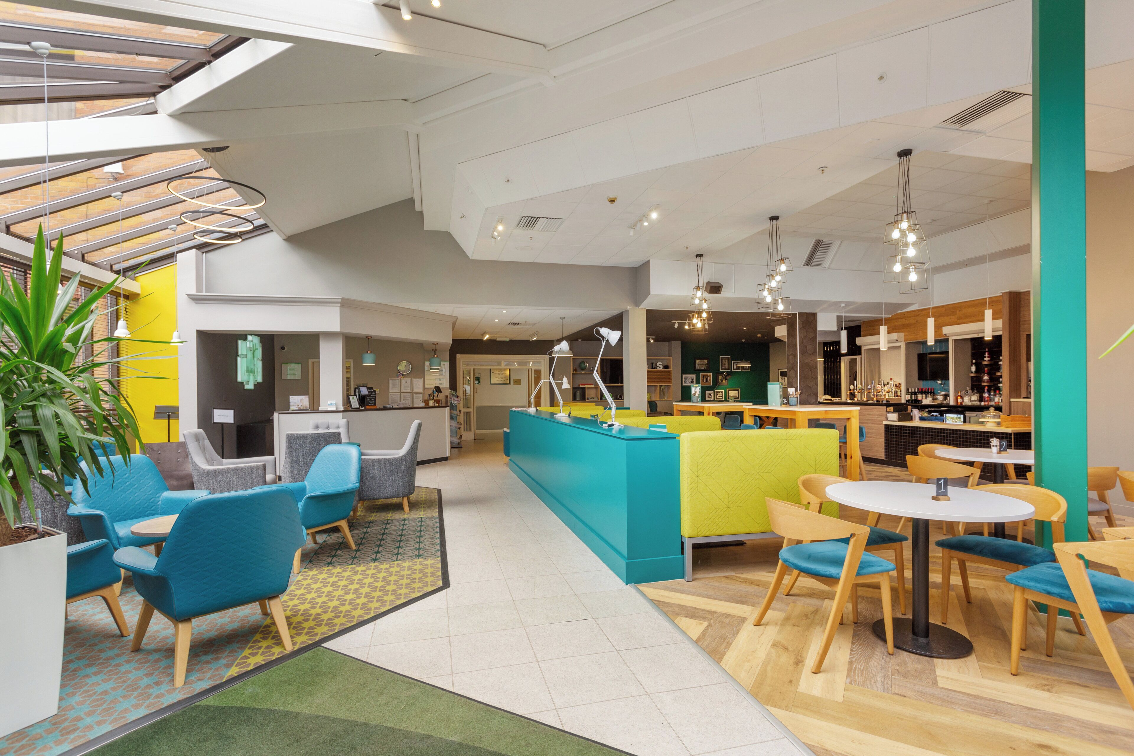 A modern interior with seating areas, a reception desk, and a bar/lounge area.