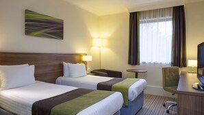 A hotel room with two beds, a desk, a chair, a lamp, and a television. - Holiday Inn Leamington Spa - Warwick by IHG (Warwick)