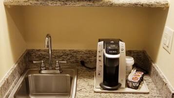 A kitchenette with a microwave, coffee maker, sink, and dishwasher.