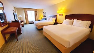 A hotel room with two beds, a desk, a chair, a television, and a lamp.