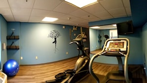 A fitness room with exercise equipment, a blue wall, and a wooden floor. - Beach Boutique Hotel (Rehoboth Beach)