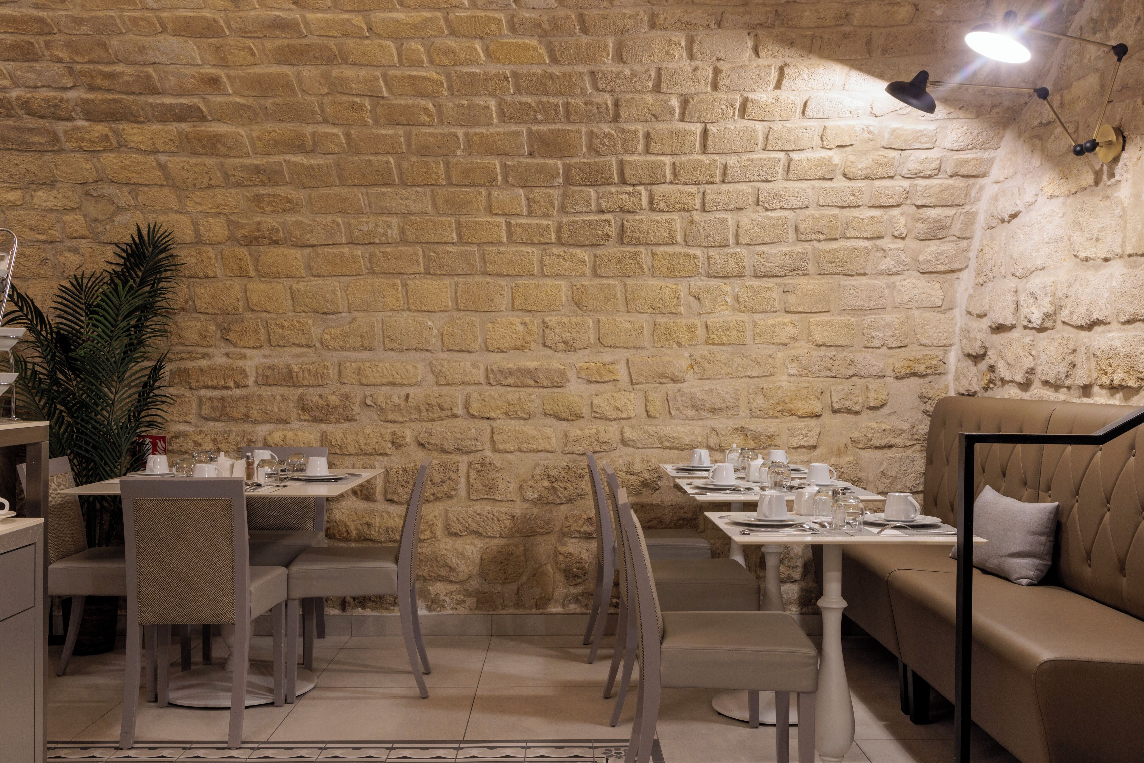 A restaurant with stone walls, tables, chairs, and a sofa.