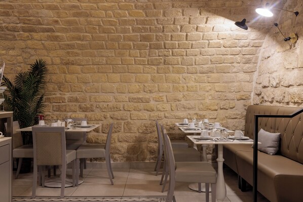 Un restaurant aux murs de pierre, avec des tables, des chaises et un canapé.