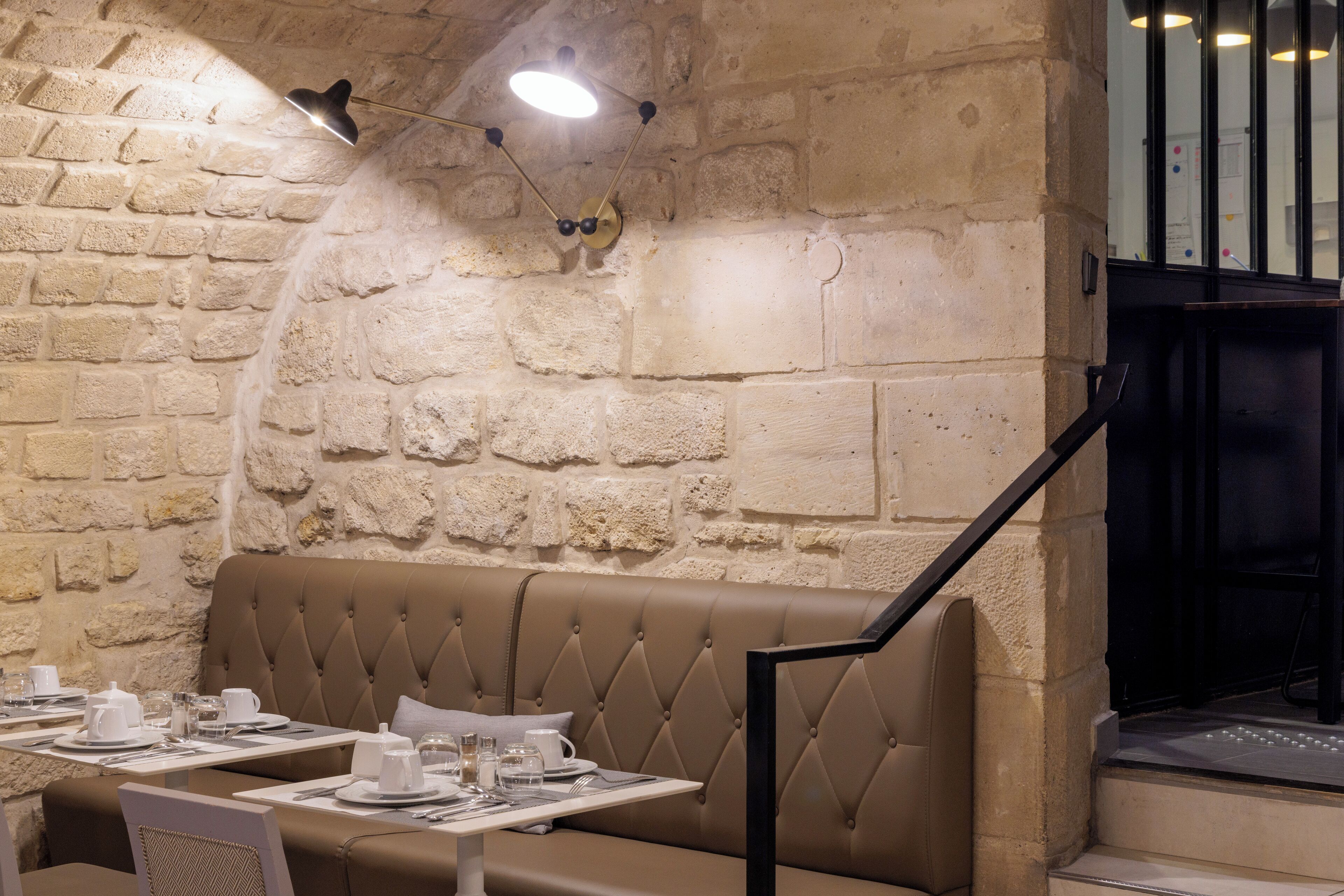 Un restaurante con pared de piedra, asientos con capitoné y mesas listas para comer.