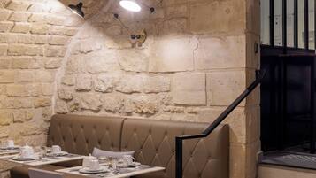 Un restaurante con pared de piedra, asientos con capitoné y mesas listas para comer.