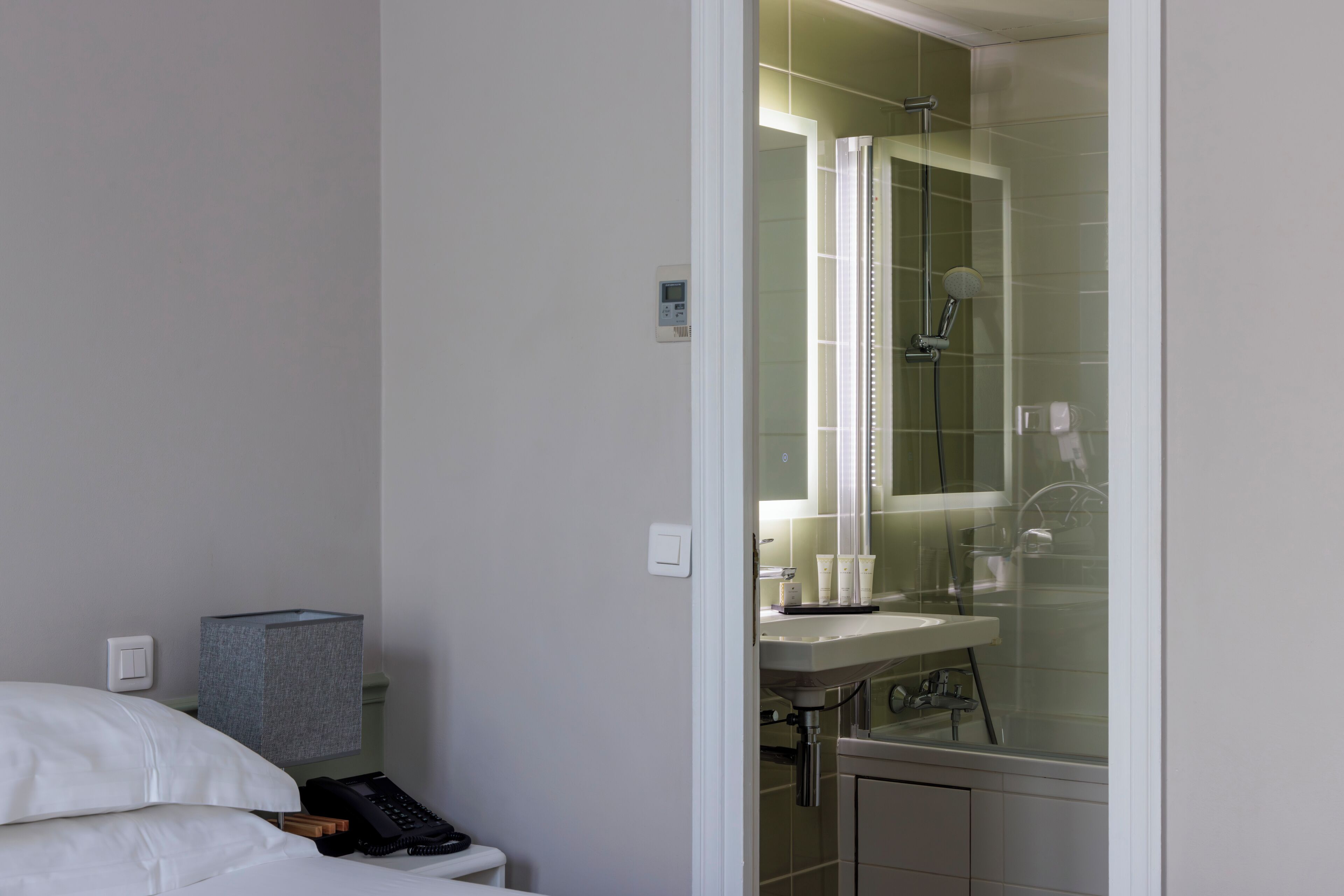 A hotel bathroom with a shower, sink, and toilet.