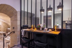 Una cocina moderna con un arco de piedra, encimera de madera, sillas negras y un espejo grande.