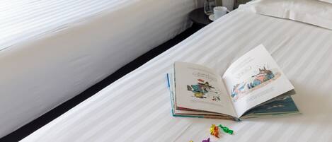 Habitación de hotel con dos camas, un libro y peluches en una de ellas.