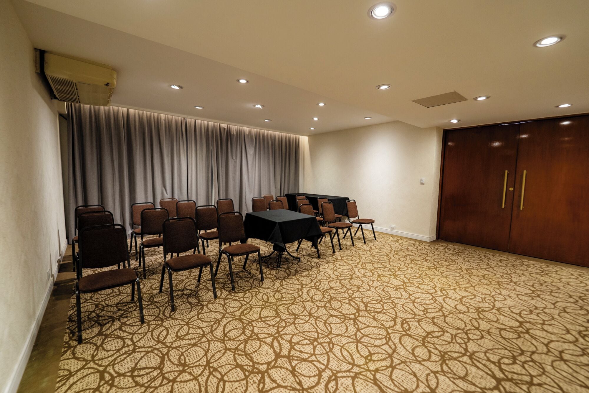A conference room with a long table and chairs, a patterned carpet, and a wooden door.