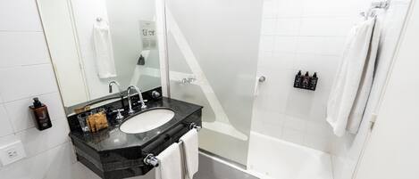 A modern bathroom with a black sink, a mirror, a glass shower enclosure, and a white bathtub.