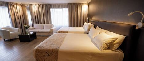 A hotel room with a large bed, a smaller bed, a sofa, and a coffee table.