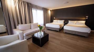 Habitación de hotel con sofá, dos camas, una mesita de centro y un florero con flores.