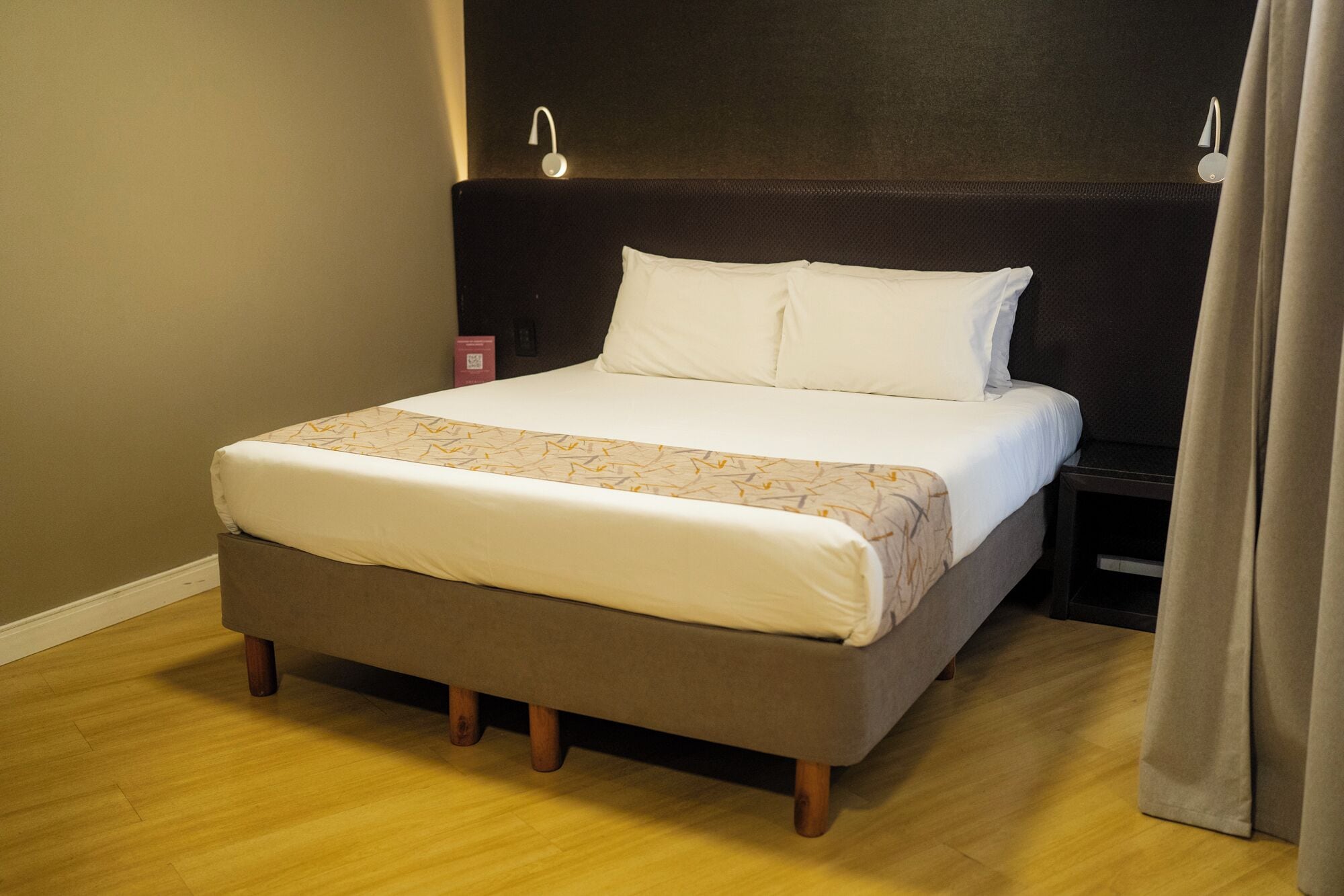 A bed with a headboard, a bedside table, and a curtain.