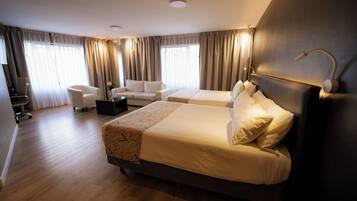 Habitación de hotel con dos camas, un sofá, una mesa de centro y un escritorio.