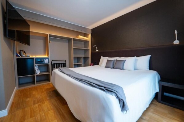 Un dormitorio con una cama grande, estanterías empotradas, un escritorio y un televisor.