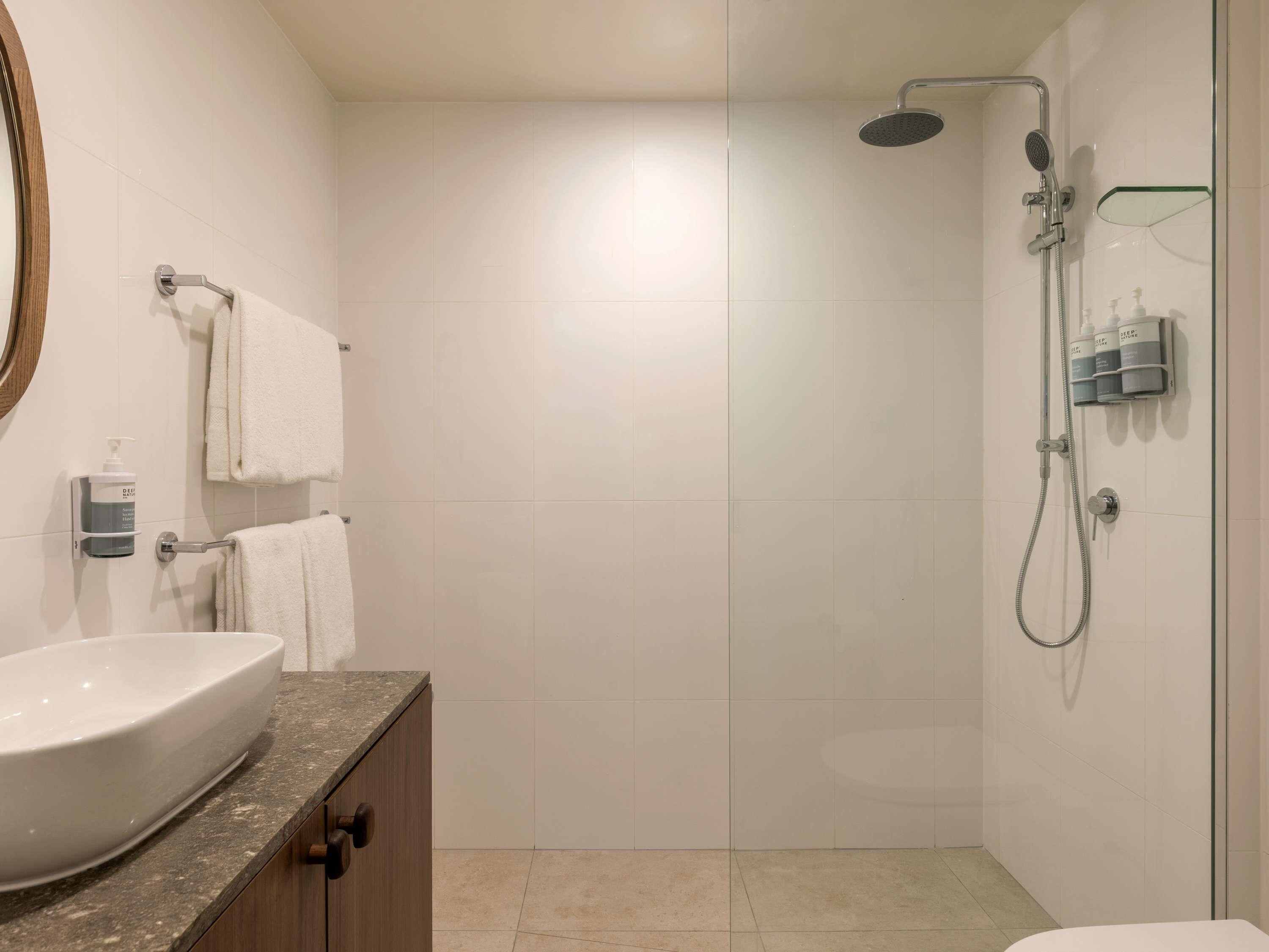 A modern bathroom with a large sink, a glass shower enclosure, and a towel rack.