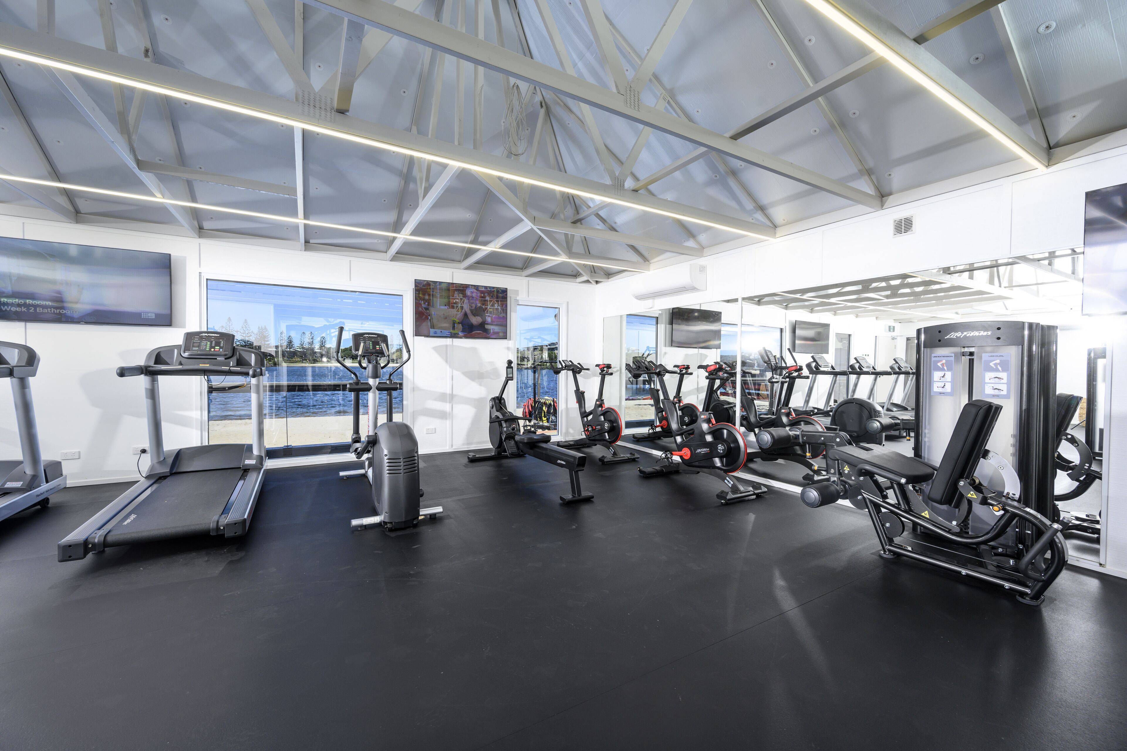 Un gimnasio con cintas de correr, elípticas y equipo de pesas.