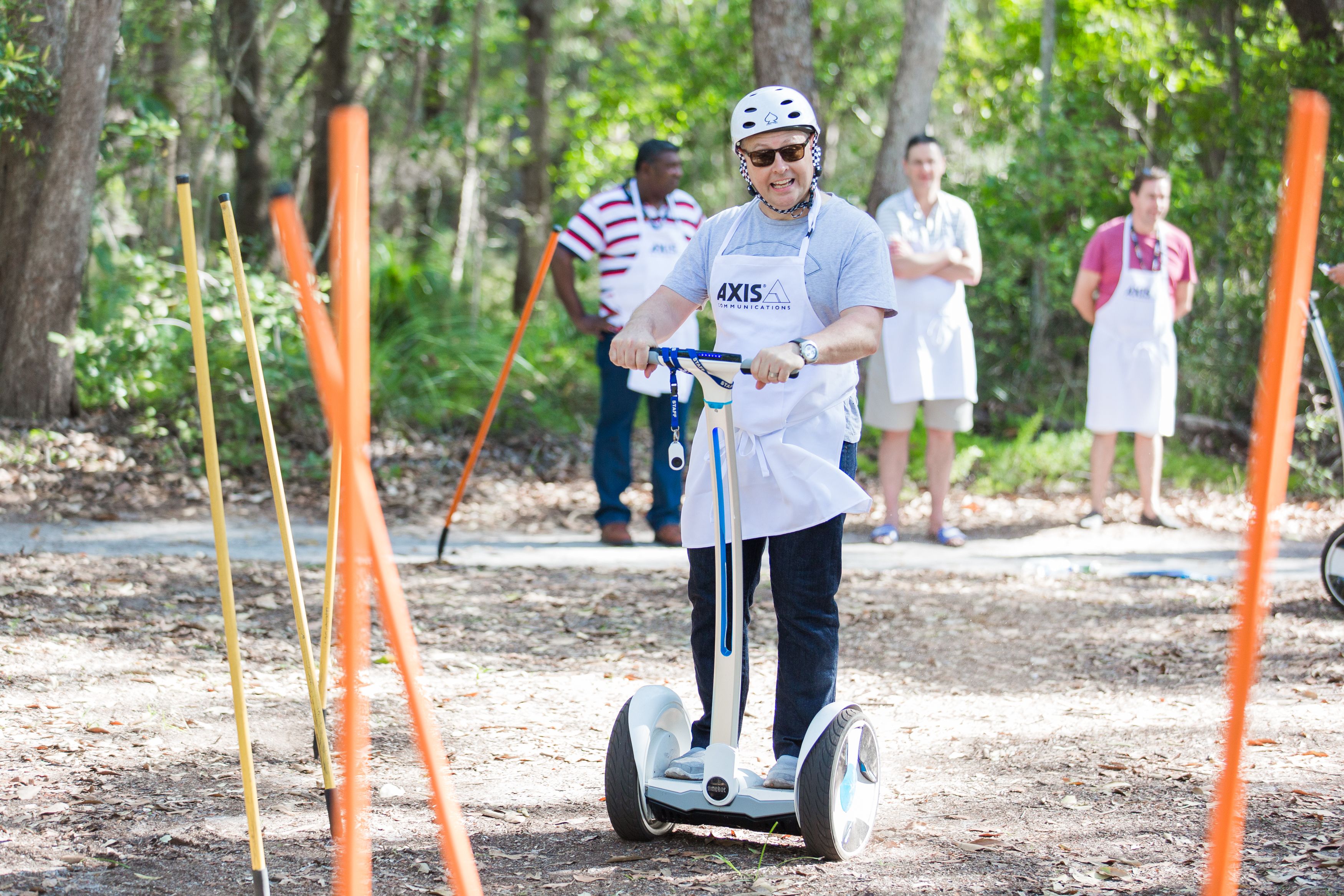 A person riding a hoverboard in a wooded area with orange poles.