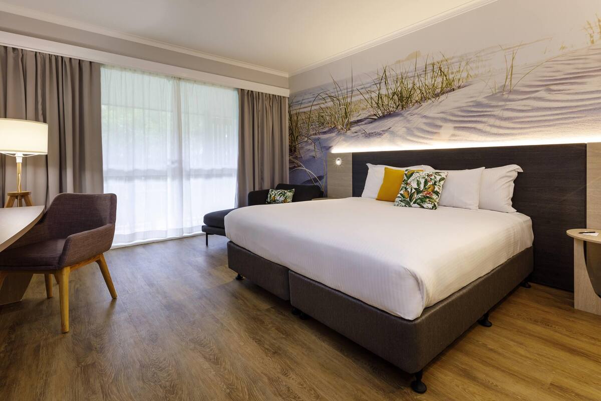 A hotel room with a large bed, a desk, and a chair.