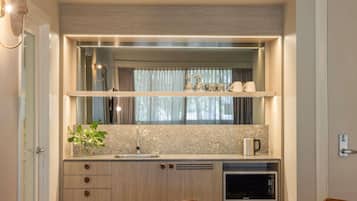 A compact kitchen with a built-in microwave, a sink, and a countertop with a plant.