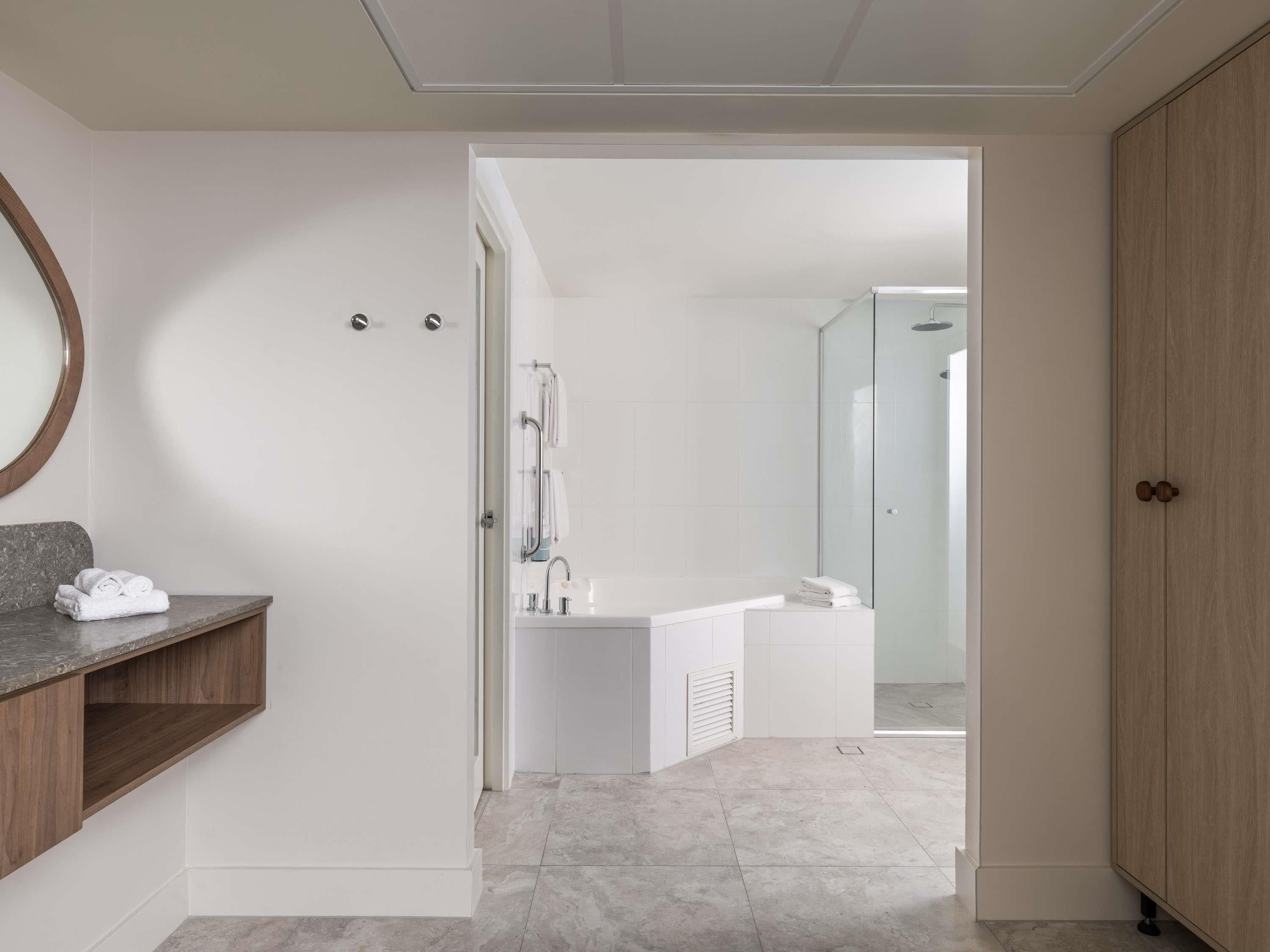 Une salle de bain moderne équipée d’une douche, d’un lavabo et d’un meuble-lavabo avec un miroir et un espace pour ranger les serviettes.