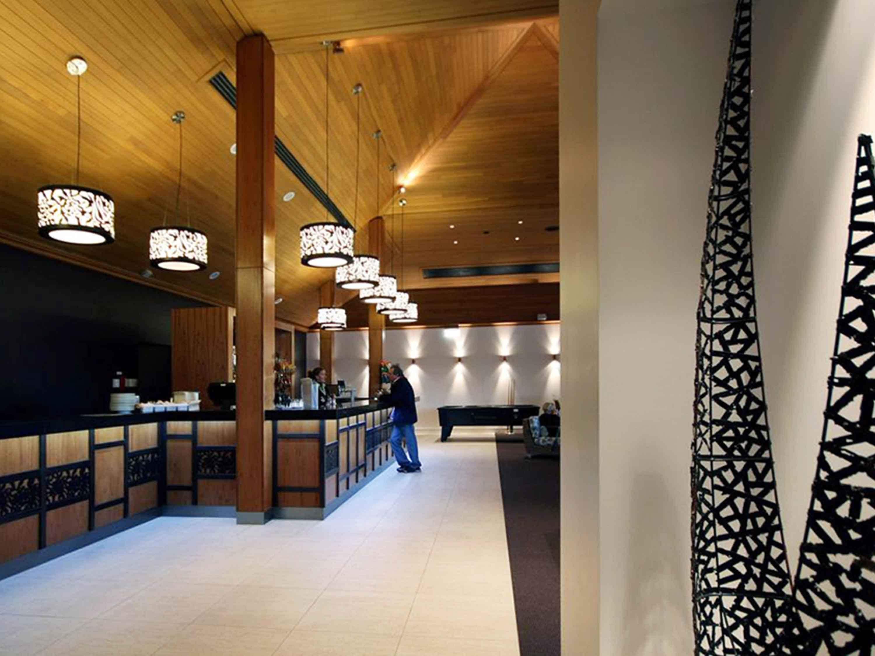 A lobby with wooden ceiling, a reception desk, and a pool table.