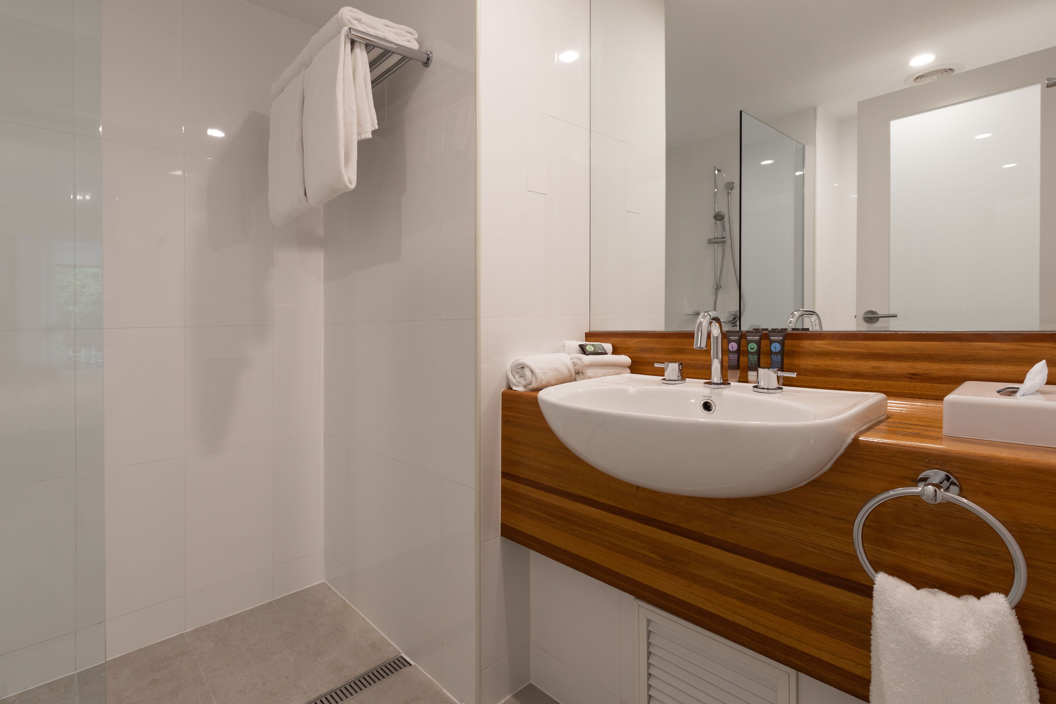 Un baño moderno con un lavamanos grande, espejo y toallero.
