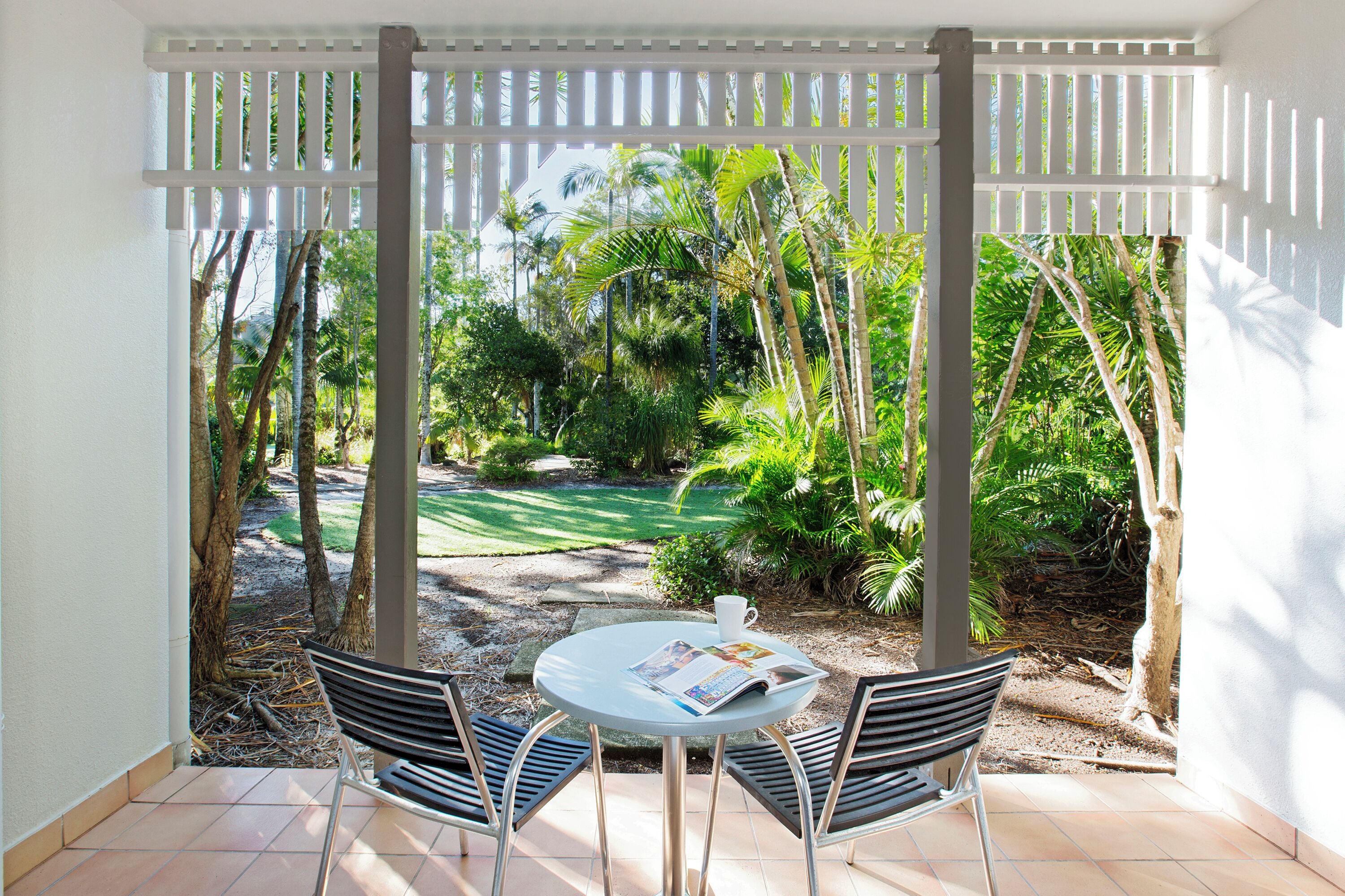 A covered patio with a round table, two chairs, and a magazine.