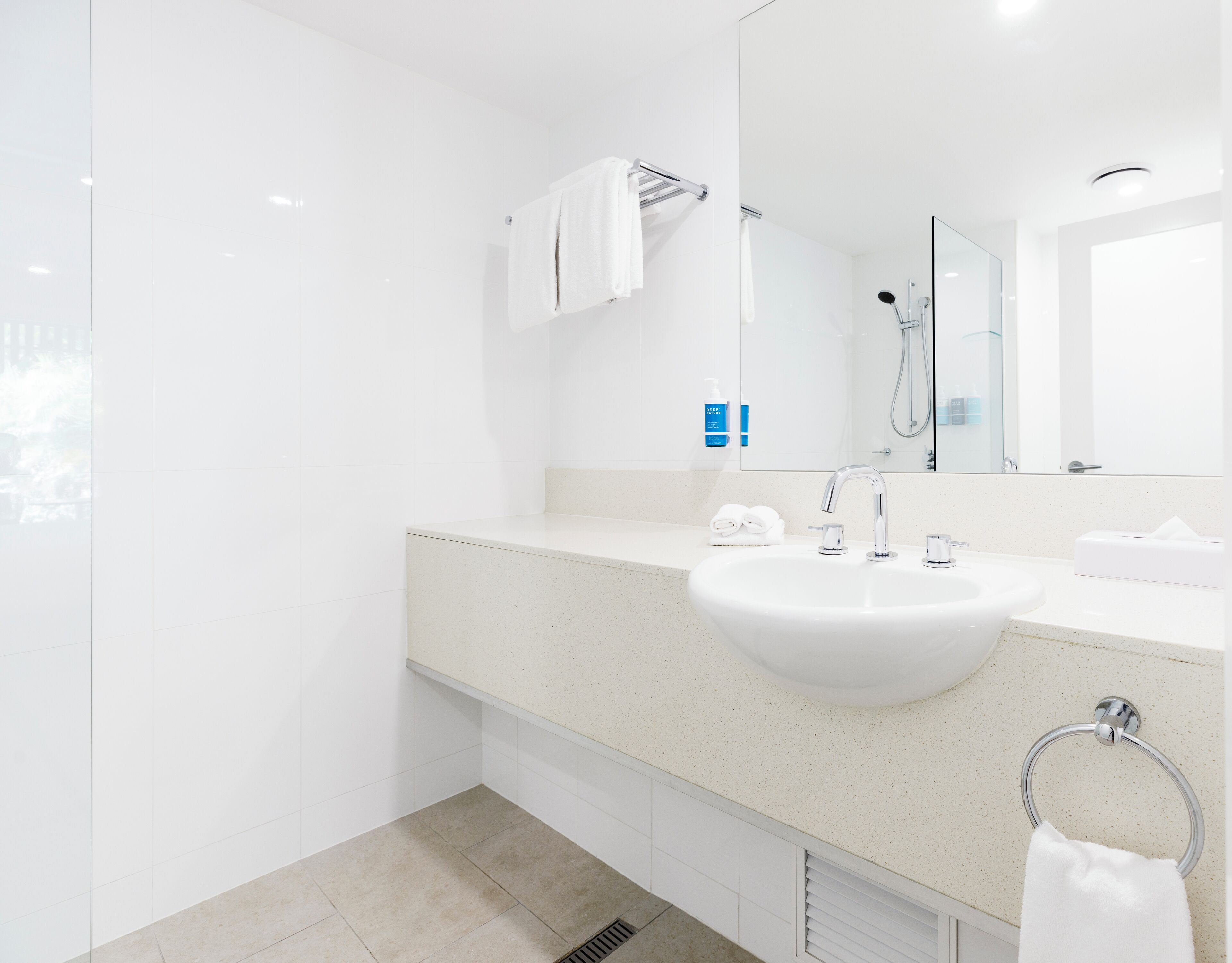 Un baño moderno con un lavamanos blanco, un espejo y una ducha.