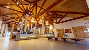 Un hall d’entrée spacieux avec un plafond haut, des poutres en bois et un comptoir d’accueil.