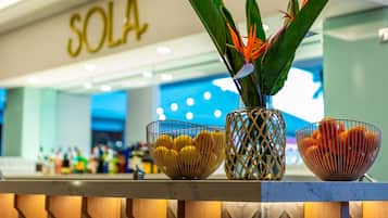 Un área de recepción con un letrero que dice 'SOLA', un mostrador de mármol y tres cuencos decorativos con frutas y una planta.