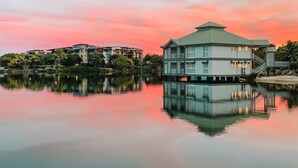 A waterfront property with multiple buildings, including a prominent house with a green roof and a balcony.