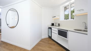 A modern kitchen with white cabinetry, a built-in dishwasher, and a large mirror.