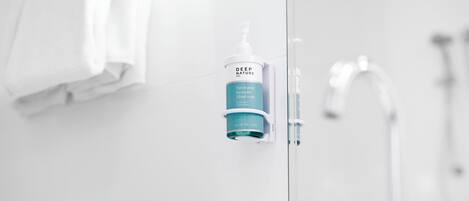 Une salle de bain équipée d’un distributeur de savon, d’un porte-serviettes et d’un miroir.