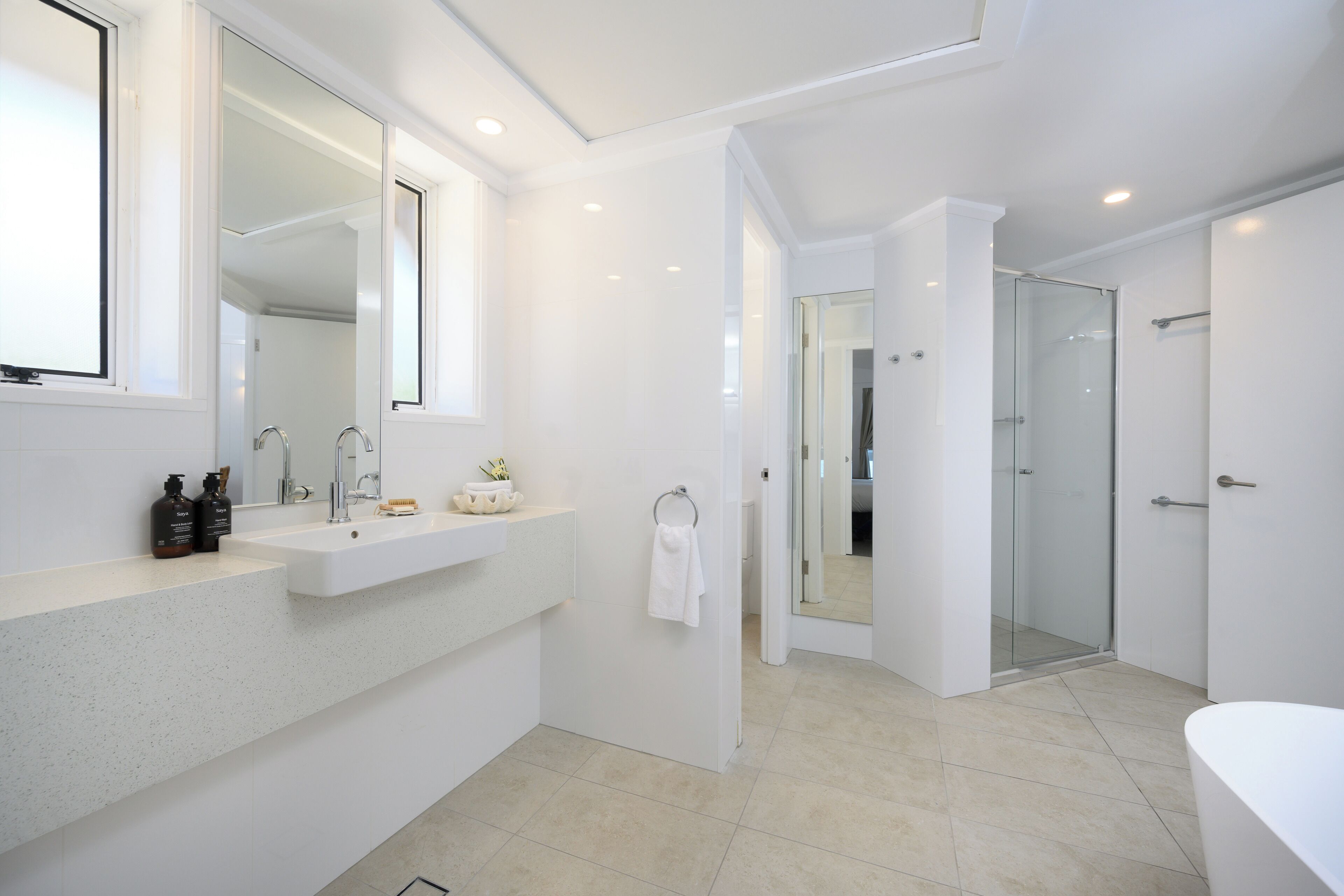 A modern bathroom with a large mirror, a sink, a shower, and a toilet.