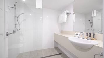 Une salle de bain moderne avec une douche à parois de verre, un lavabo blanc et un grand miroir.