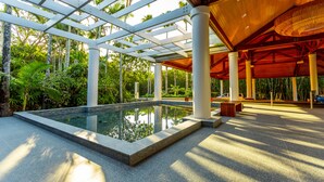 Zwembadgedeelte met glazen omheining, omgeven door palmbomen en een houten pergola.