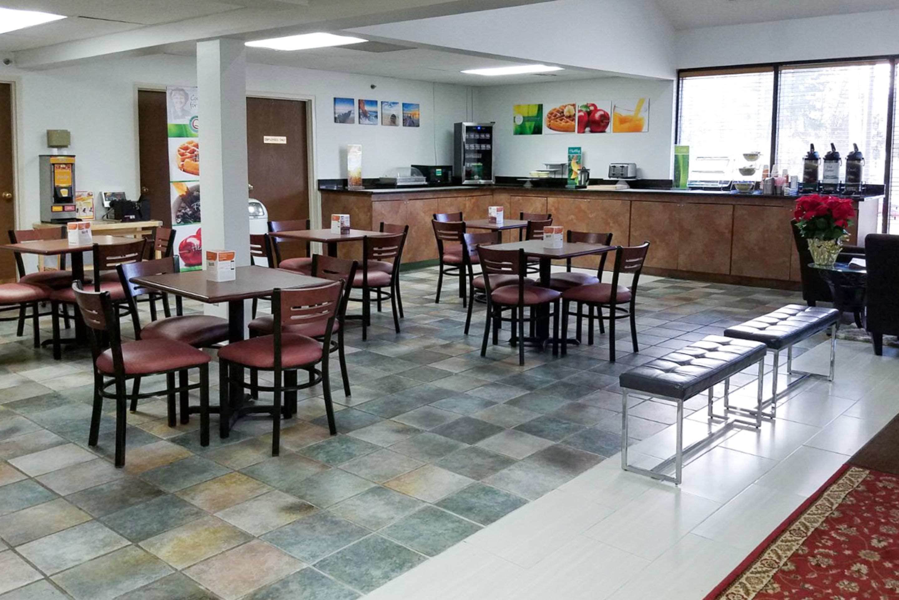 Un restaurant avec plusieurs tables et chaises, un comptoir avec une caisse enregistreuse et une fenêtre donnant sur un paysage agréable.