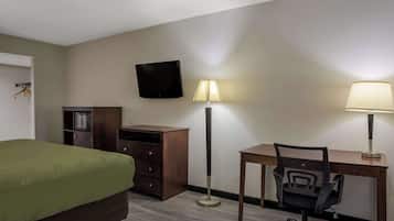 Une chambre d’hôtel équipée d’un lit, d’un bureau, d’une chaise, d’une télévision et de deux lampadaires.