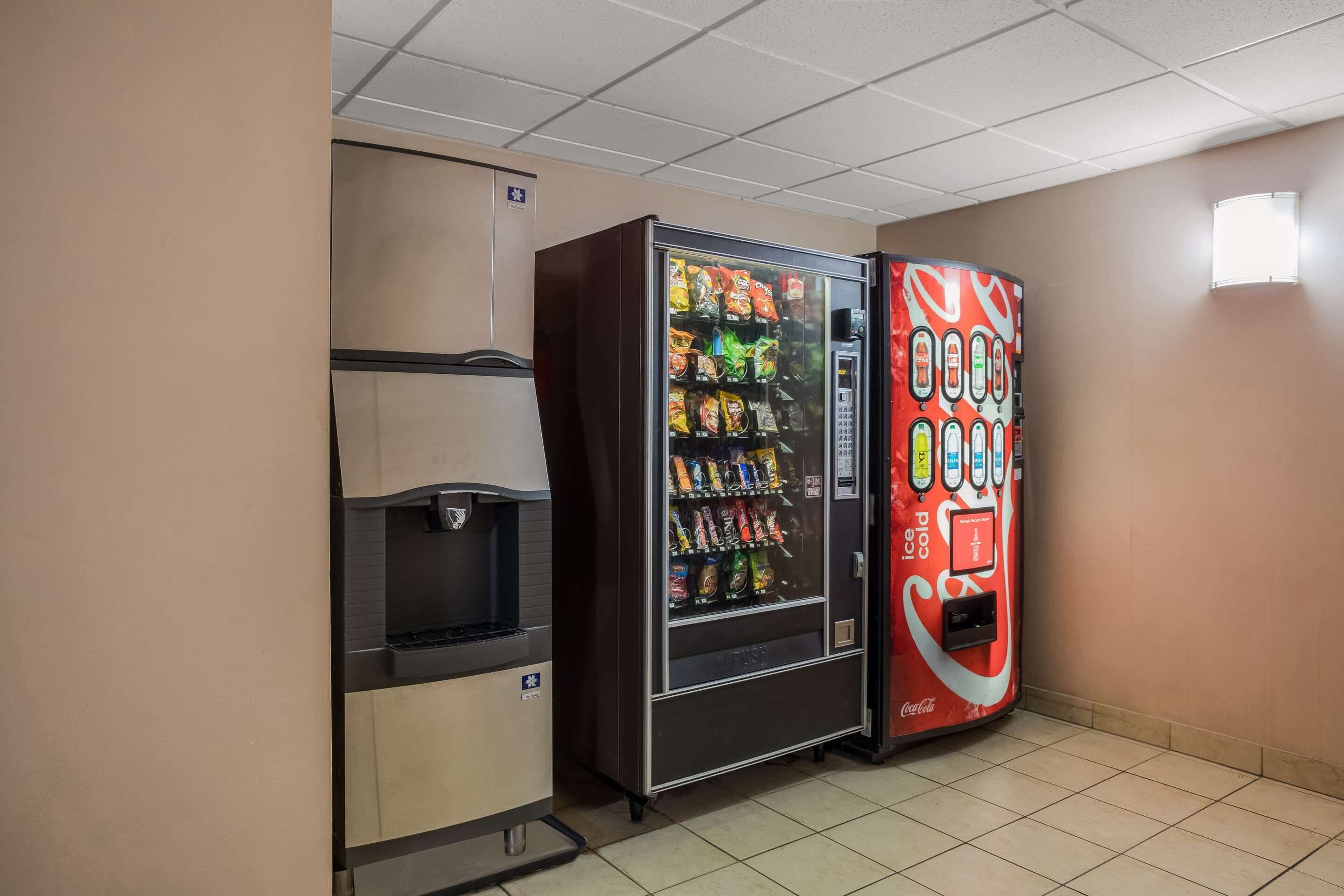 Myyntiautomaattialue, jossa on juoma-automaatti ja Coca-Colan brändillä varustettu automaatti.