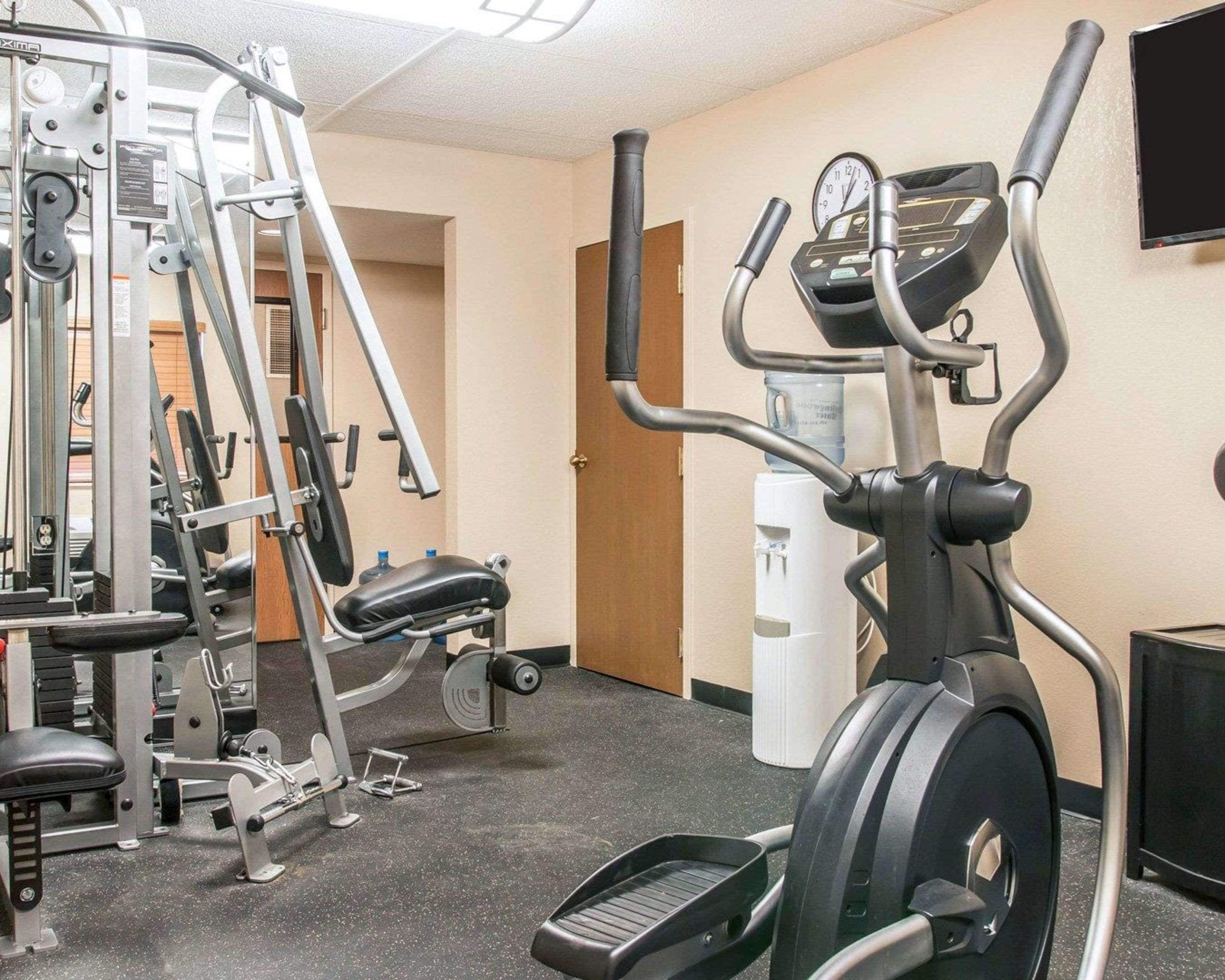 Un gimnasio con equipo de cardio, máquinas de pesas y un dispensador de agua.