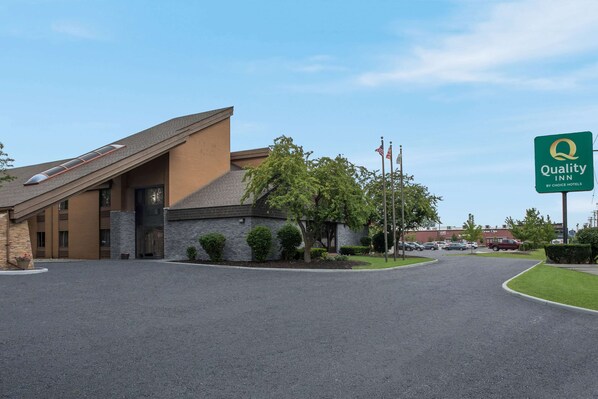 A Quality Inn by Choice Hotels building with a modern design, including a sloped roof and a large parking lot.