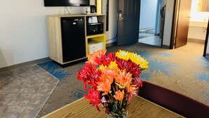 A hotel room with a flat-screen TV, a minibar, a wooden cabinet, and a floral arrangement on a table. - Days Inn by Wyndham Jamestown (Jamestown)