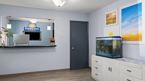 A hotel room with a bed, a desk with a computer, a fish tank, and a door. - Days Inn by Wyndham Jamestown (Jamestown)